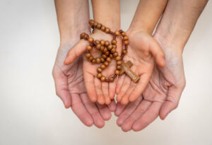 Adult and child hands holding rosary beads